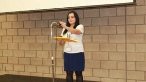 Woman in a ToLSO shirt holding folders while speaking at a microphone.