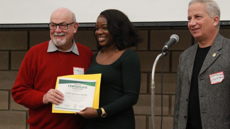 A ToLSO participant receiving a certificate from organizers on stage.