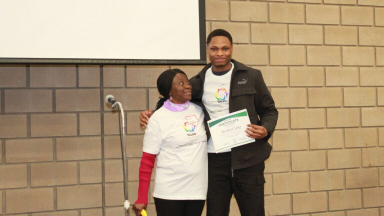 A young man accepting a ToLSO participation certificate on stage.