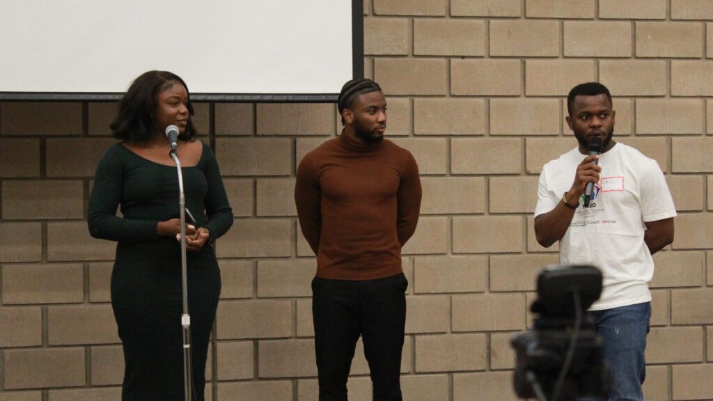 Three young people speaking as a panel at a microphone.