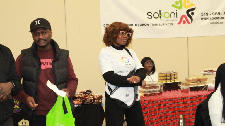 A man holding a food-program bag beside an organizer in a ToLSO shirt at the event.