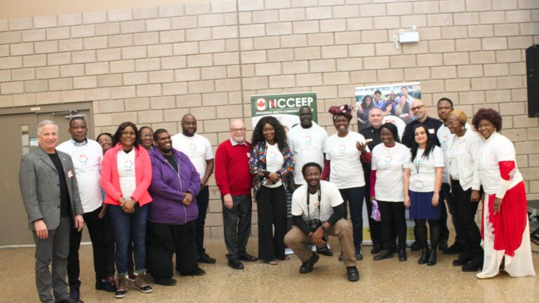 Large group in ToLSO shirts posing beside an NCCEEP banner.