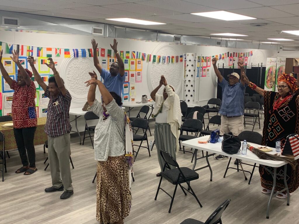 Attendees on their feet with arms raised for the exercise session at the WEBS Centre in the Windsor hall