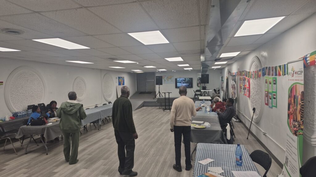 A wide view of the hall on Tecumseh Road in Windsor, with attendees seated at the gingham-covered tables and others standing and chatting